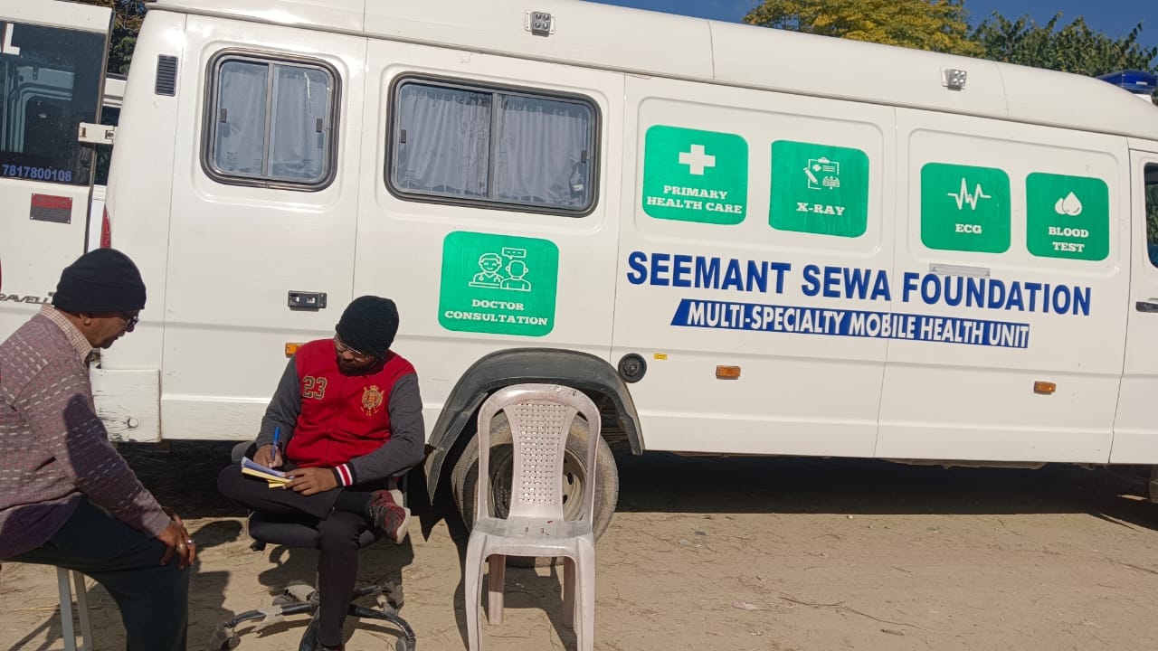 Seemant Sewa Foundation Mobile Medical Unit in the background while doctors provide healthcare services to patients