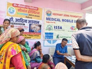 Doctor writing prescription during Seemant Sewa Foundation free rural medical camp in Uttarakhand while patients wait for consultation in remote Himalayan village