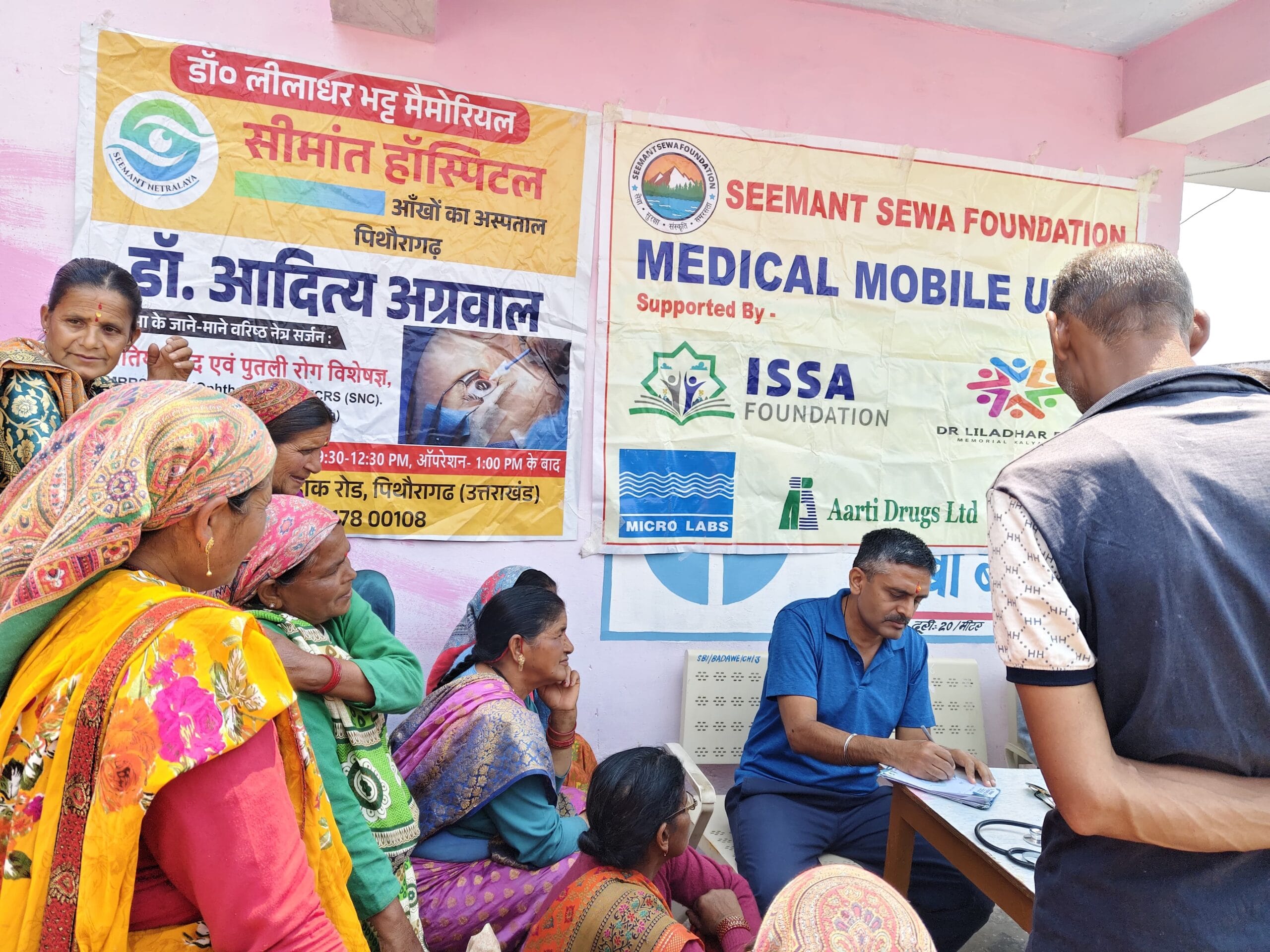 Doctor writing prescription during Seemant Sewa Foundation free rural medical camp in Uttarakhand while patients wait for consultation in remote Himalayan village