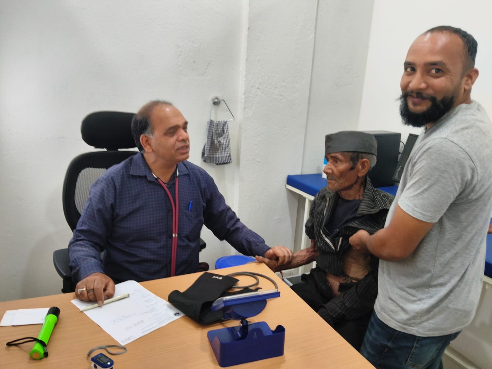 Doctor examining an elderly patient at Seemant Poly Clinic accompanied by a family member